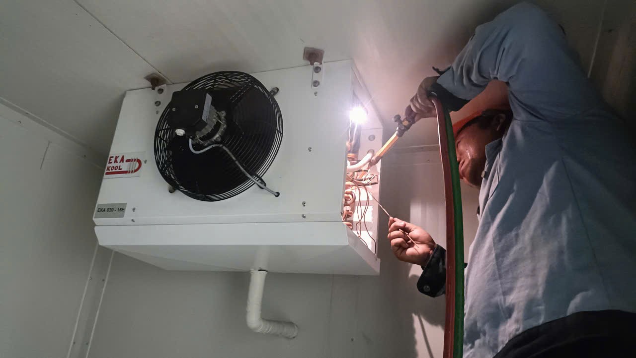 refrigeration technician repairing industrial freezer