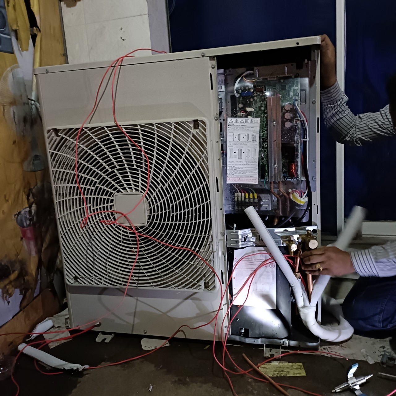technician repairing air conditioner outdoor unit