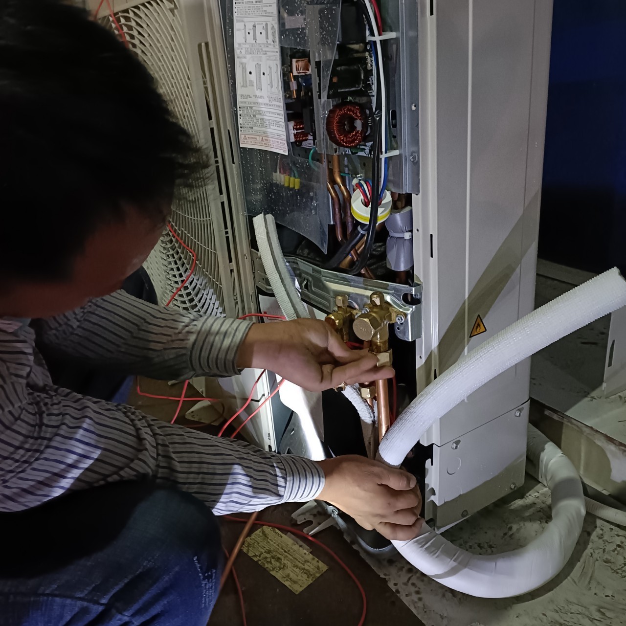 technician repairing air conditioner outdoor unit