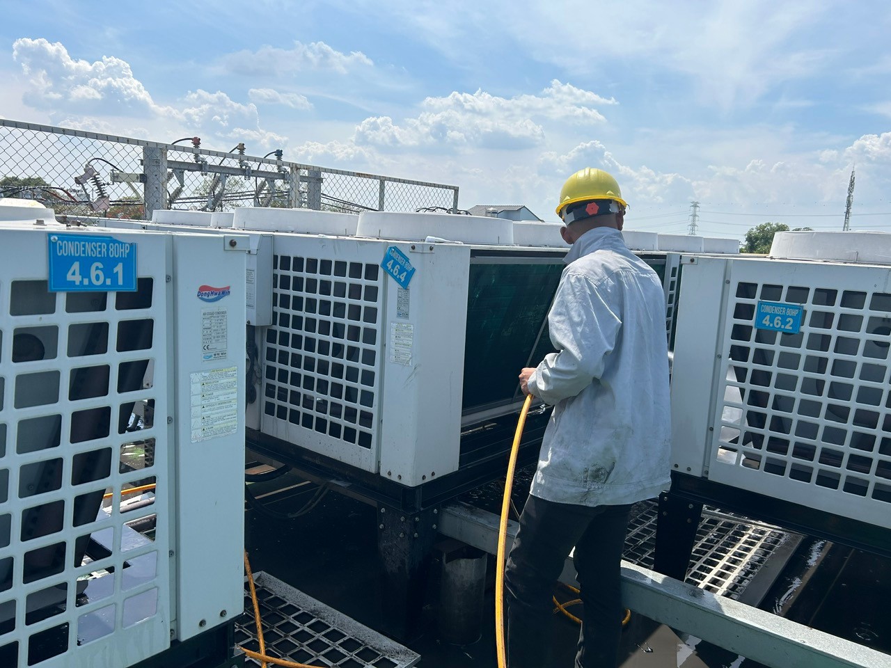 technician using pressure washer to clean air conditioner coil